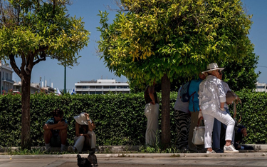 Turyści chronią się przed słońcem na placu Syntagma w stolicy Grecji, Atenach, podczas fali upałów w