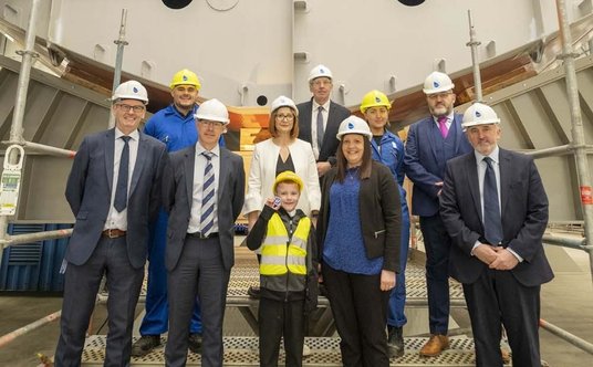 Pamiątkowa fotografie pracowników Babcocka i Josha Duffy'ego z pamiątkową monetą na tle pierwszej se