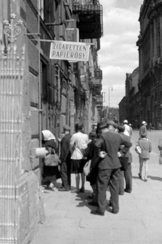 Ludzie stojący w kolejce do sklepu w kamienicy przy Kredytowej 14 (po północnej stronie pl. Dąbrowsk