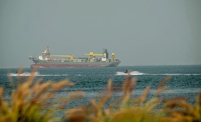 Turyści jadą na skuterach wodnych obok zakotwiczonych statków handlowych u wybrzeży Dubaju, 2 marca 