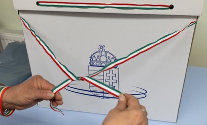 Urzędnik przewiązuje urnę wyborczą wstążką w narodowych barwach przed rozpoczęciem wyborów w Dunakes