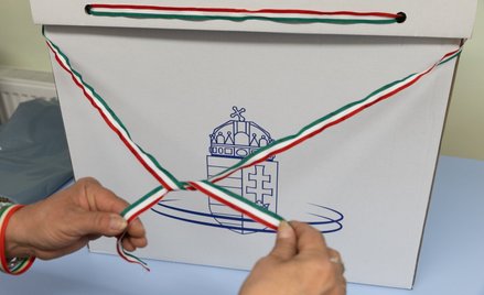 Urzędnik przewiązuje urnę wyborczą wstążką w narodowych barwach przed rozpoczęciem wyborów w Dunakes