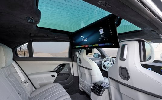 Tylna kanapa BMW 740 xDrive i panoramiczny ekran umożliwiający oglądanie filmów niemal jak w kinie.