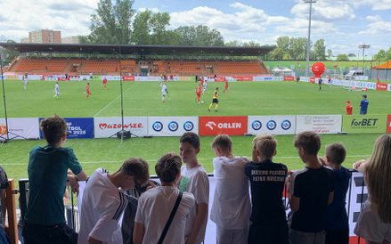 Młodzi kibice z bliska śledzą zmagania na murawie, zainspirowani grą zawodników