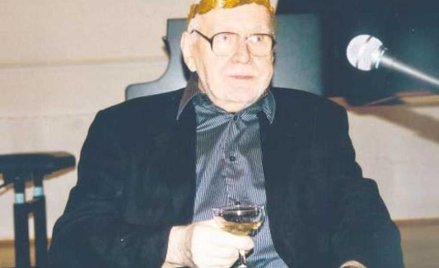 Artysta w laurowym wieńcu na głowie wznosi toast za zdrowie gości