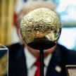 Donald Trump siedzi przed złotym modelem Księżyca