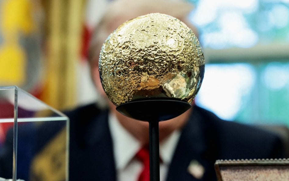Donald Trump siedzi przed złotym modelem Księżyca