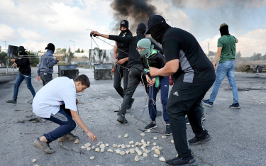 Palestyńczycy w Ramallah używają proc do rzucania kamieniami w izraelskich żołnierzy