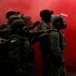 Funkcjonariusze organów ścigania pośród dymu z granatu dymnego użytego do rozpędzenia demonstrantów 