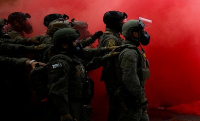 Funkcjonariusze organów ścigania pośród dymu z granatu dymnego użytego do rozpędzenia demonstrantów 