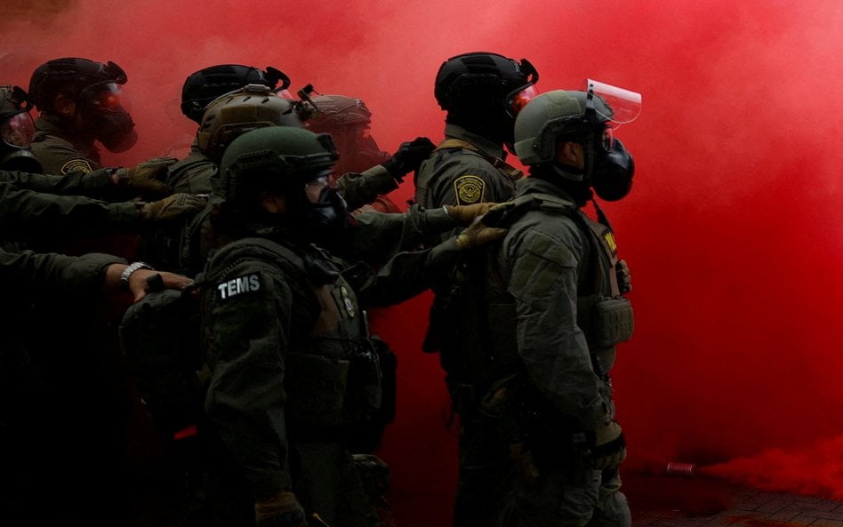 Funkcjonariusze organów ścigania pośród dymu z granatu dymnego użytego do rozpędzenia demonstrantów 