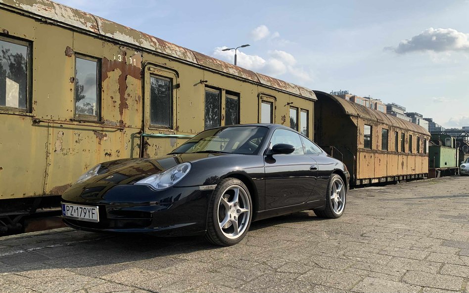 Klasyczne, czarne Porsche 911 (generacji 996) elegancko zaparkowane obok zardzewiałych, zabytkowych 