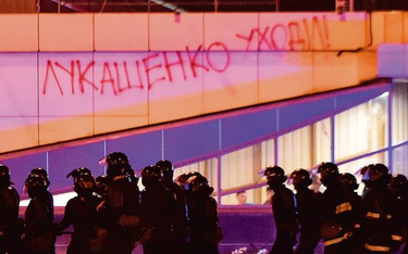 Pacyfikacja ulicznych protestów w Mińsku. W tle napis: „Łukaszenko odejdź”
