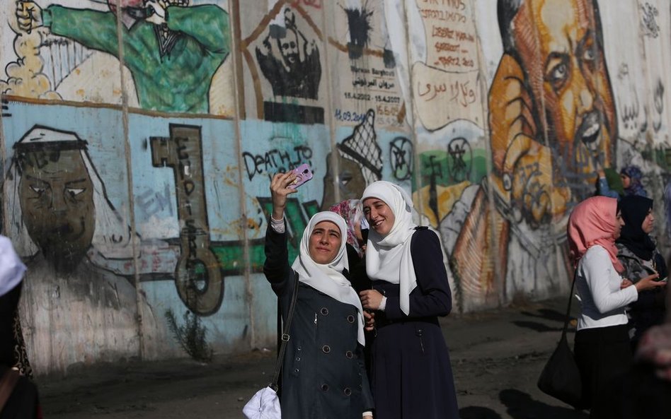 Palestyńskie kobiety robiące „selfie” w pobliżu punktu kontrolnego między Ramallah i Jerozolimą. Wie