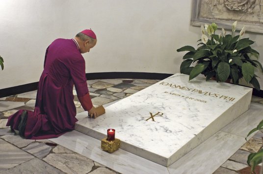 Abp Stanisław Dziwisz u pierwotnego grobu Jana Pawła II w Grotach Watykańskich kładzie na płycie swó