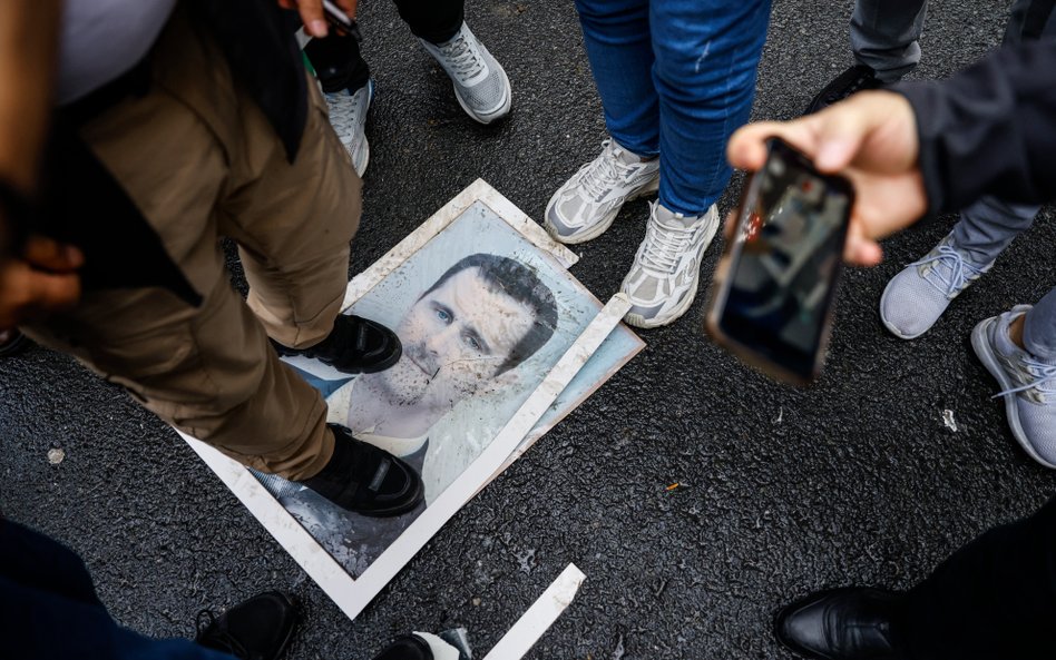 Demonstranci stoją na zdjęciu Baszara Asada podczas protestu przed syryjskim konsulatem w Stambule. 