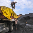 Pracownicy zabezpieczają plandekę na ciężarówce załadowanej węglem w porcie Krishnapatnam w stanie A