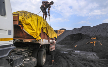 Pracownicy zabezpieczają plandekę na ciężarówce załadowanej węglem w porcie Krishnapatnam w stanie A