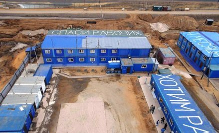 Napisy na kontenerowych domkach robotników kosmodromu. U góry "Ratuj robotników", z prawej strony cz