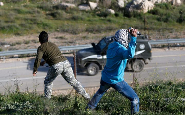 Młodzi Palestyńczycy obrzucają izraelskie samochody wojskowe na Zachodnim Brzegu Jordanu
