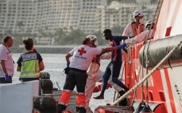 Pracownicy Czerwonego Krzyża pomagają migrantom wysiąść ze statku hiszpańskiego ratownictwa morskieg