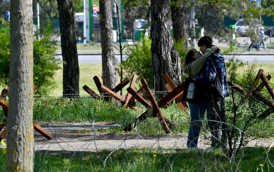 Młoda para w parku na obrzeżach Kijowa, gdzie obrona przeciwczołgowa, okopy, ziemianki i drut kolcza