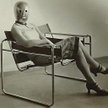 Tajemnicza kobieta w fotelu zaprojektowanym przez Marcela Breuera, w masce Oskara Schlemmera i stroj