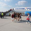 Klienci biur podróży przesiadają się z autokarów do samolotów