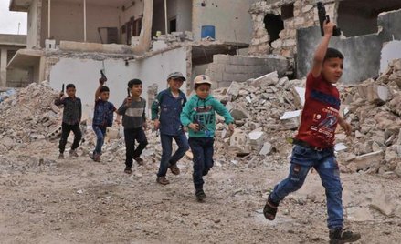 Dzieci bawią się w wojnę w zniszczonej miejscowości w prowincji Aleppo. Tereny północnej Syrii doświ