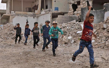 Dzieci bawią się w wojnę w zniszczonej miejscowości w prowincji Aleppo. Tereny północnej Syrii doświ