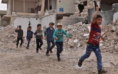 Dzieci bawią się w wojnę w zniszczonej miejscowości w prowincji Aleppo. Tereny północnej Syrii doświ