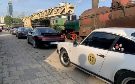 Rząd Porsche na tle zabytkowych lokomotyw