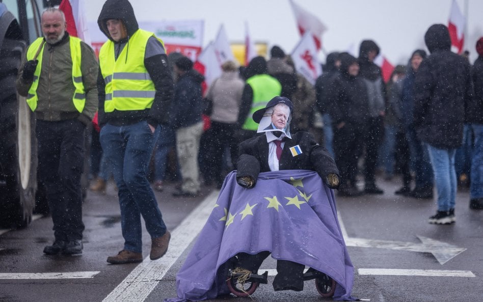 Słomiany manekin z twarzą komisarza UE ds. rolnictwa Janusza Wojciechowskiego siedzi na wózku inwali