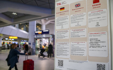 Tablica z informacjami nt. koronawirusa w językach niemieckim, angielskim i chińskim na lotnisku Ber