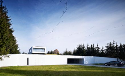 Rozwiązanie z ukrytym wjazdem do domu to wynik ukształtowania działki, która ma spory spadek. Archit