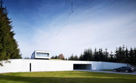 Rozwiązanie z ukrytym wjazdem do domu to wynik ukształtowania działki, która ma spory spadek. Archit