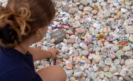 Osoby odwiedzające miejsce pamięci kładą kamyki ku czci ofiar masowej strzelaniny na plaży Bondi