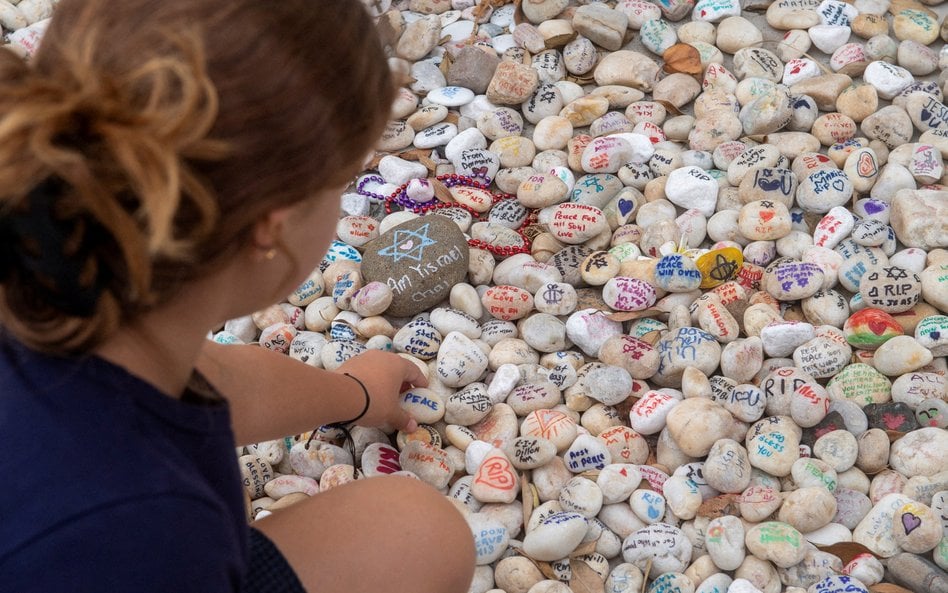 Osoby odwiedzające miejsce pamięci kładą kamyki ku czci ofiar masowej strzelaniny na plaży Bondi
