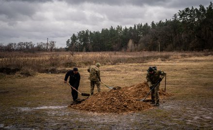 Ukraińscy żołnierze i cywil zakopują trumnę z ciałem ukraińskiego żołnierza, poległego w walkach w o