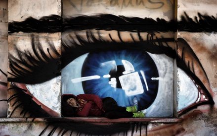 Kobieta śpiąca przed graffiti ilustrującym oko, w porcie Mytilene na greckiej wyspie Lesbos.