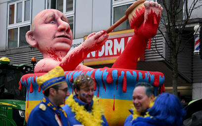 Uczestnicy karnawału ubrani w barwy Ukrainy przed platformą przedstawiającą Władimira Putina biorące