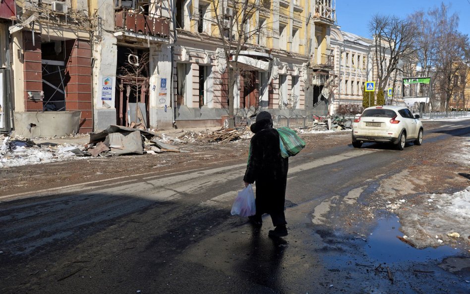 Kobieta na ulicy zniszczonego bombardowaniami i ostrzałem Charkowa