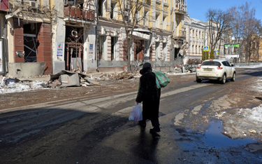 Kobieta na ulicy zniszczonego bombardowaniami i ostrzałem Charkowa
