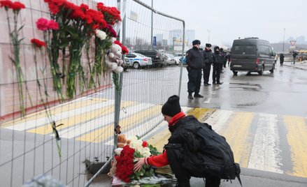Pod budynkiem okoliczni mieszkańcy symbolicznie składają kwiaty i znicze