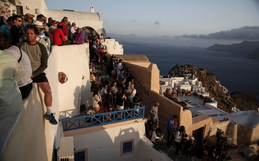 Turyści oglądający zachód słońca w mieście Oia na wyspie Santorini