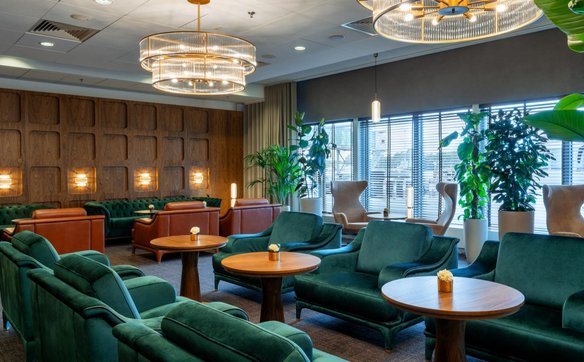 Przestronna część wypoczynkowa z wygodnymi, welurowymi kanapami w odcieniach zieleni i brązu. Okna z