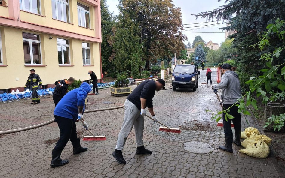 więźniowie usuwają skutki podtopień