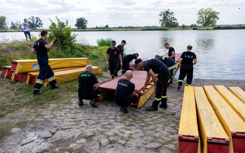 Strażacy ustawiają specjalną zaporę, której zadaniem będzie zatrzymywanie śniętych ryb płynących z n