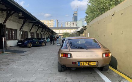 Klasyczne Porsche 928 w kolorze złotym, z charakterystycznymi lampami