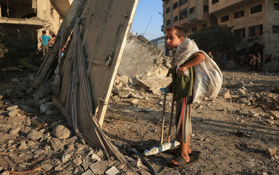 Palestyńskie dziecko obok zniszczone przez wojsko Izraela domu w mieście Gaza